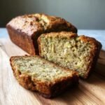 Close-up of moist banana bread with zucchini, showing visible green zucchini shreds within the loaf.