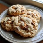 A close-up of soft and chewy butterscotch chocolate chip cookies piled on a plate.