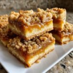 A stack of delicious Caramel Crumb Bars with a gooey caramel filling and crumbly topping.