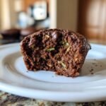 Close-up of a moist Chocolate Zucchini Cupcake with chocolate chips and visible zucchini shreds.