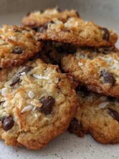 A close-up stack of freshly baked Coconut Chocolate Chip Cookies, showing melted chocolate chips and shredded coconut.