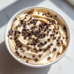 Overhead view of creamy Peanut Butter Cheesecake Dip topped generously with mini chocolate chips in a white bowl.