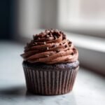 A rich double chocolate banana cupcake topped with chocolate frosting and mini chocolate chips.