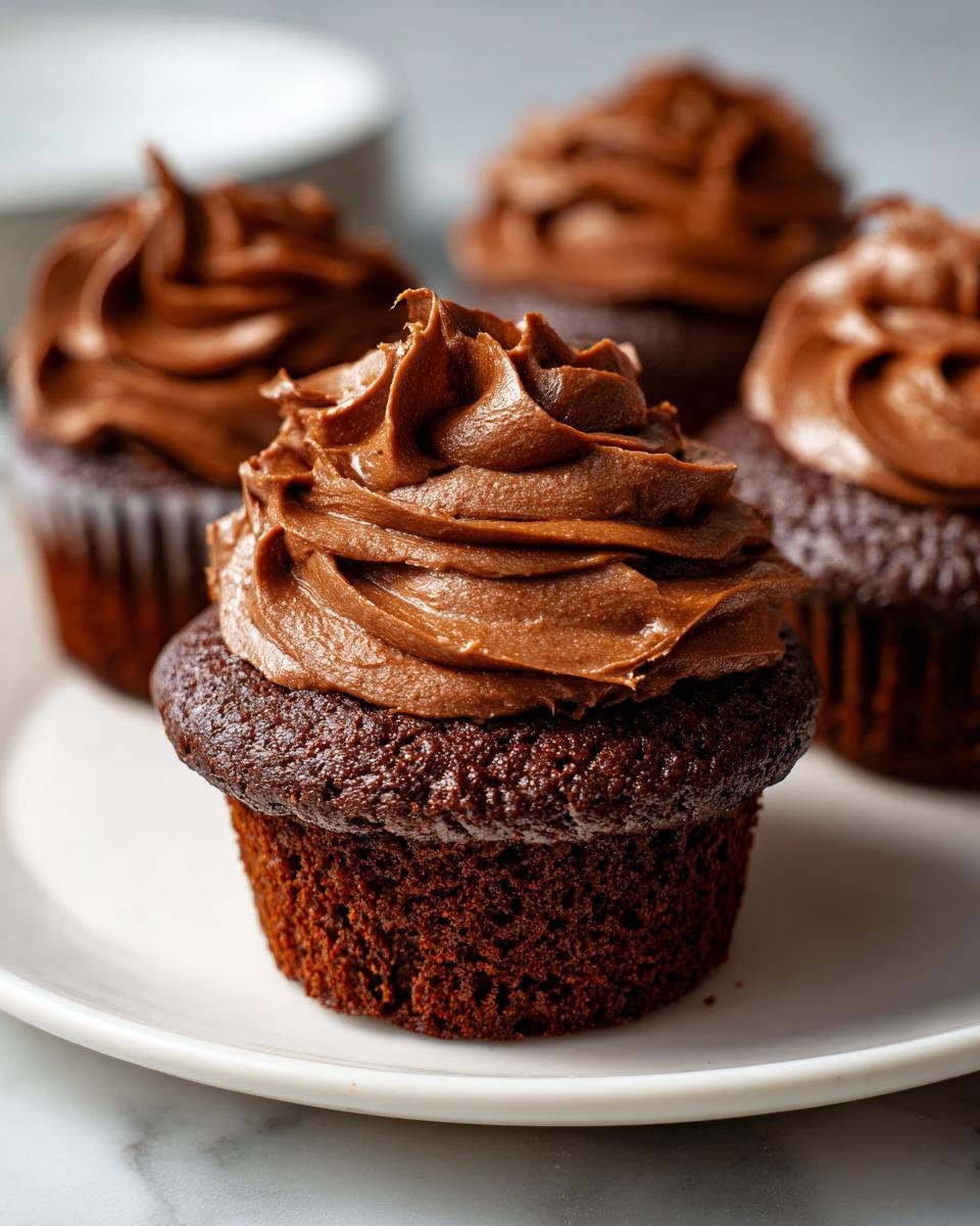A close-up of a rich, dark chocolate Nutella Cupcakes topped with a generous swirl of chocolate frosting.