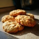 A close-up shot of a stack of golden-brown Peanut Butter Oatmeal Cookies, with visible oats and a slightly crinkled texture.