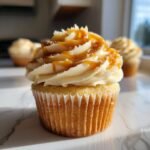 Close-up of a delicious Pumpkin Cupcake topped with creamy caramel cream cheese frosting and a caramel drizzle.
