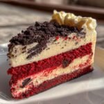 A decadent slice of Red Velvet Oreo Cheesecake with layers of red velvet cake, creamy cheesecake filling, and Oreo crumbles.