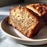 A close-up of a moist slice of rum soaked cake on a plate, showing its tender crumb and golden crust.