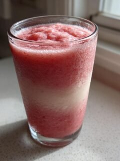 A frosty glass filled with a layered Strawberry Banana Smoothie, condensation visible on the exterior.