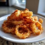 A pile of golden brown, crispy Air Fryer Fried Calamari rings served on a white plate.