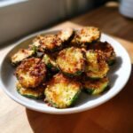 A pile of golden brown, crispy Air Fryer Zucchini Crisps served on a white plate.
