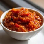 Close-up of vibrant, chunky Ajvar Roasted Red Pepper Spread served in a small white bowl.