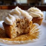 Close-up of an Apple Cinnamon Cupcakes cut in half showing moist crumb and creamy frosting.