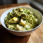 Close-up of chunky Avocado Chicken Egg Salad mixed with herbs in a white bowl.