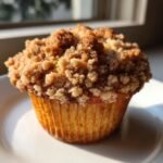 Close-up of a freshly baked Banana Streusel Muffins featuring a thick, golden brown crumb topping.