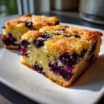 Two slices of moist, buttery Blueberry Cookie Bars studded with dark purple blueberries, served on a white plate.