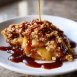 Close-up of a serving of Caramel Apple Crumble topped with a thick stream of caramel sauce.