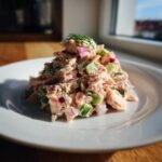 A mound of creamy Chopped Salmon Salad mixed with celery and red onion, garnished with fresh dill.
