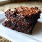 Close-up of a thick, fudgy slice of dark Chocolate Brownies with a shiny, crackled top.