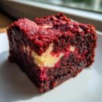 Close-up of a fudgy, deep red Red Velvet Brownies square with a visible cream cheese swirl.