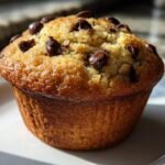 Close-up of a perfectly baked, golden brown Chocolate Chip Muffins with visible chocolate chips on top.