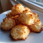 A pile of freshly baked, golden brown Coconut Macaroons showing toasted edges and shredded coconut texture.