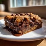 Close-up of a gooey Chocolate Chip Cake Bars slice on a white plate with melted chocolate oozing out.