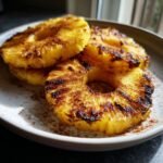 Close-up of Irresistible Grilled Pineapple Recipe slices dusted with cinnamon on a white plate.