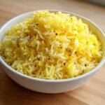 Close-up of fluffy, bright yellow Lemon Rice topped generously with fresh lemon zest.