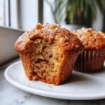 Close-up of a moist Apple Muffins with a bite taken out, showing texture and sugar crystals.