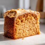 Close-up of a thick slice of moist Peanut Butter Cake topped with creamy peanut butter frosting.