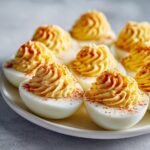 A plate of My Favorite Deviled Eggs featuring creamy, piped filling dusted with paprika.