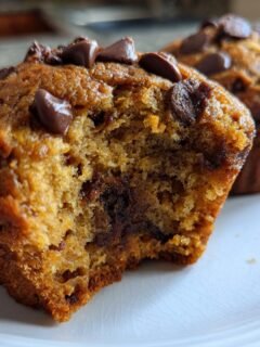 Close-up of a Peanut Butter Chocolate Chip Muffin with a bite taken out, showing soft interior and melted chips.