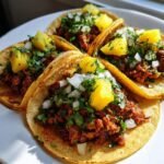Four delicious Tacos Al Pastor With Ground Turkey topped with pineapple, onion, and cilantro on a white plate.