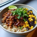 Close-up of a Vegan BBQ Jerk Jackfruit Chipotle Burrito Bowl with rice, black beans, corn, and cilantro.