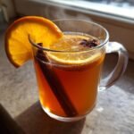 Close-up of a steaming mug of Cozy Mulled Apple Cider garnished with an orange slice, cinnamon stick, and star anise.