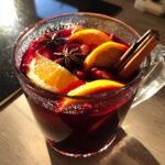 Close-up of a Cozy Spiced Winter Sangria in a glass mug, garnished with orange slices, star anise, and a cinnamon stick.