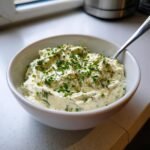 A close-up of a bowl filled with creamy Garlic And Herb Dip Dairy Free, topped with fresh chives and dill.