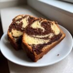Two slices of Easy And Moist Marble Cake showing beautiful chocolate and vanilla swirls on a white plate.