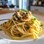 A close-up of Easy Canned Tuna Pasta tossed in oil and topped with flaked tuna and fresh parsley.