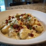 Close-up of a bowl of Easy Creamy Brie and Bacon Gnocchi coated in a rich sauce and topped with crispy bacon bits.