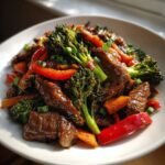 Close-up of Irresistible Beef And Vegetable Stir Fry with glossy sauce, broccoli, and red peppers.