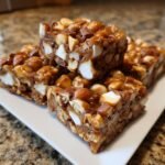 Close-up of stacked squares of Irresistible Caramel Apple Rocky Road Delight loaded with nuts, marshmallows, and caramel.
