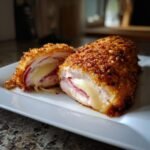 A crispy, golden-brown Irresistible Chicken Cordon Bleu recipe cut open showing melted cheese and ham inside.
