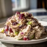 A mound of creamy Irresistible Cranberry Turkey Salad featuring shredded turkey, dried cranberries, celery, and red onion.
