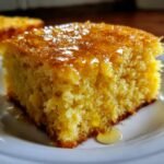 Close-up of a moist slice of Irresistible Honey Butter Cornbread drizzled heavily with a shiny honey butter glaze.