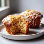 Close-up of an Irresistible Lemon Poppy Seed Muffin with a bite taken out, showing the moist crumb and lemon glaze.