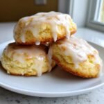 Three Irresistible Lemon Ricotta Cookies stacked on a white plate, generously drizzled with a thick lemon glaze.