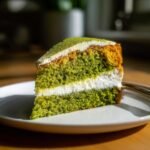 A perfect slice of Irresistible Matcha Cake featuring vibrant green layers, white cream filling, and matcha dusting.