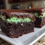 Two slices of Irresistible Mint Chocolate Brownies showing a dark chocolate base, bright green mint layer, and chocolate ganache topping.